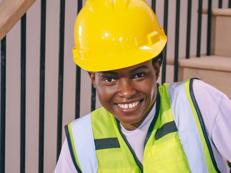 Smiling worker in a hard hat and safety vest on a job site
