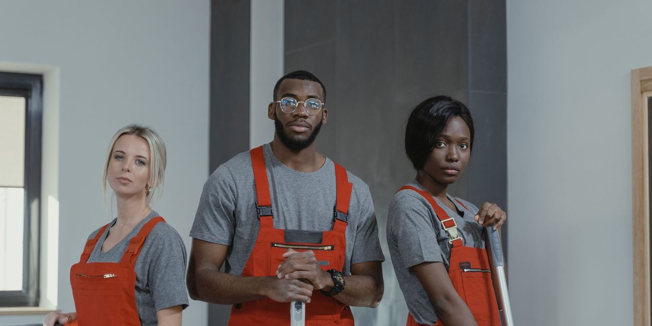 Three uniformed cleaning professionals with mops and equipment
